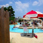 Lifeguard stand with red and white umbrella looks over pool at waterpark
