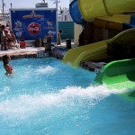 Water splashes from waterslide as woman waits in the pool