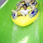 Son and father slide down waterslide at waterpark