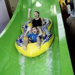 Mother and son wave hi as sliding down waterslide at waterpark