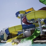 Woman holds on to raft as she splashes from waterslide