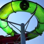 Visitor traveling through green spiral tube of waterslide
