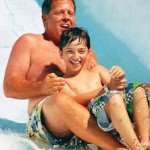 Father and son hold tight as sliding down waterslide
